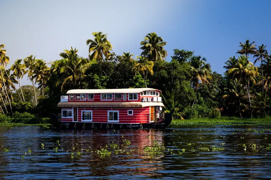 Traditional Kerala houseboat cruising the Alappuzha backwaters past palm-lined shores