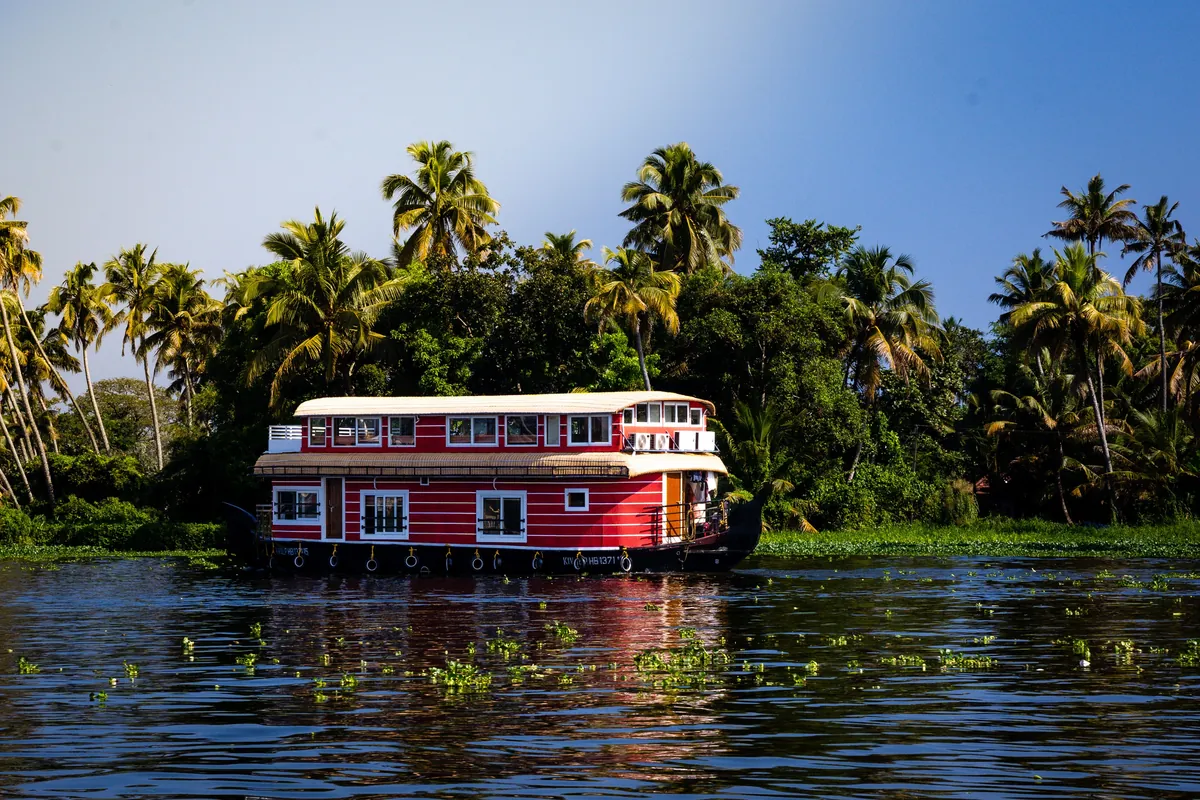 Traditional Kerala houseboat cruising the Alappuzha backwaters past palm-lined shores