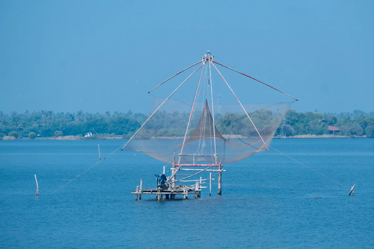 A cantilevered Chinese fishing net over calm water at Fort Kochi, Kerala