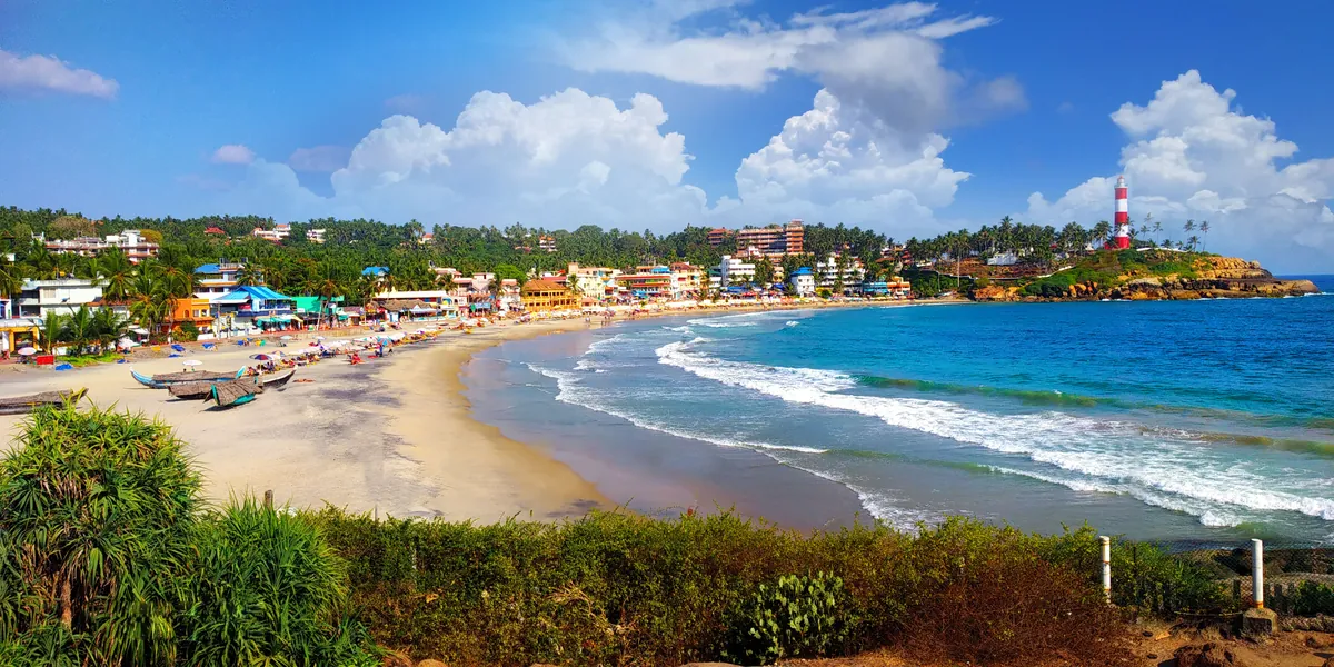 The crescent sweep of Kovalam beach with golden sand and the lighthouse, Kerala